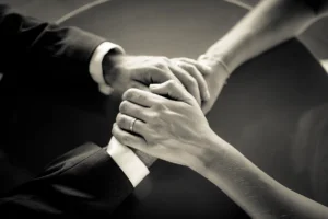 Mains des mariés entrelacées avec alliances, détail mariage noir et blanc