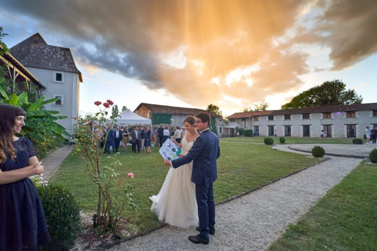 Les mariés dans le jardin du Château de Beauséjour, à Saint-Léon-sur-l'Isle, au coucher du soleil devant les bâtiments en pierre