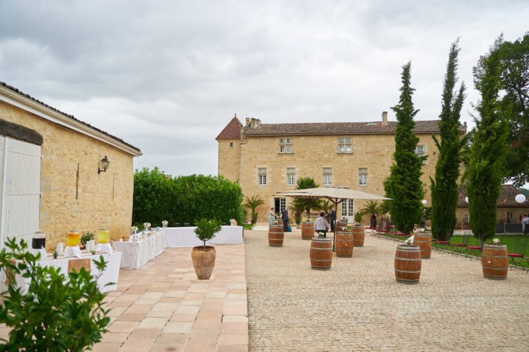 Cour en pierre du Château Isabeau de Naujan, à Saint-Vincent-de-Pertignas, avec ses tonneaux et ses cyprès