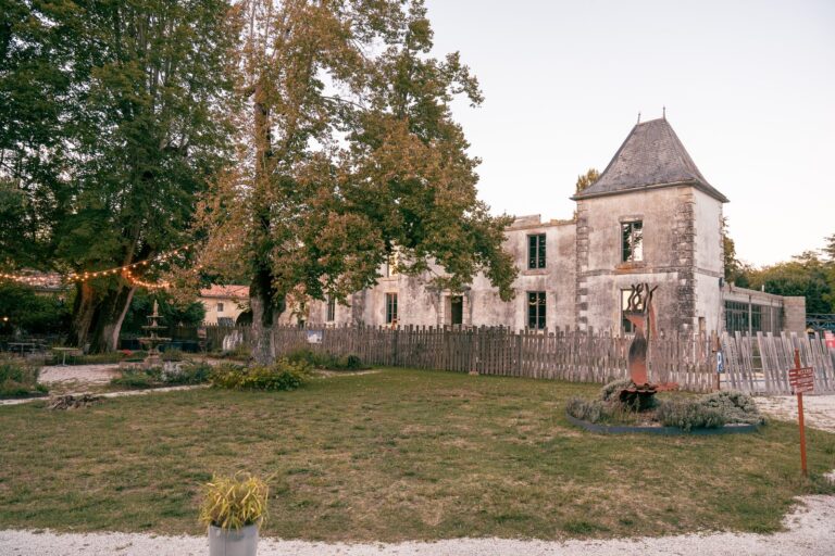Le château du Domaine du Seudre à Saint-Germain-du-Seudre, avec sa tourelle en pierre au milieu des arbres du parc.