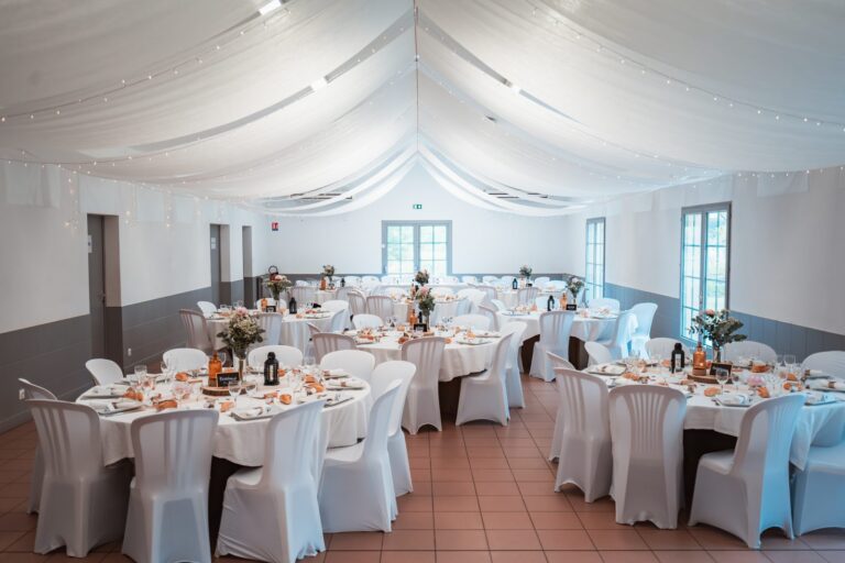 Salle de l'Amicale des sapeurs-pompiers de Bordeaux Métropole, à Ludon-Médoc, avec ses tables rondes dressées sous des drapés blancs