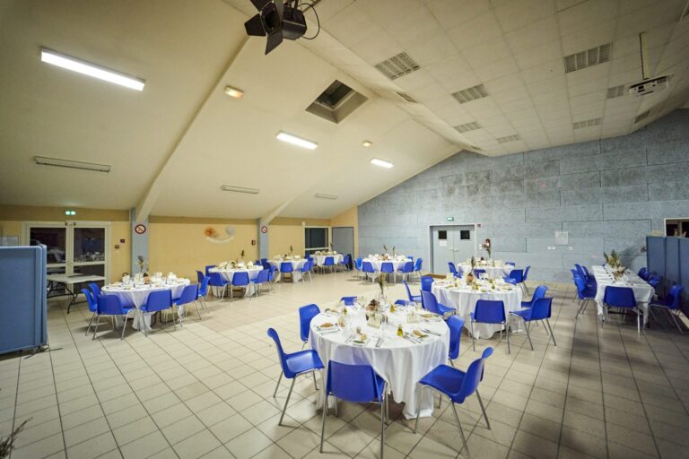 Salle des fêtes de Virelade avec ses tables rondes dressées et ses chaises bleues