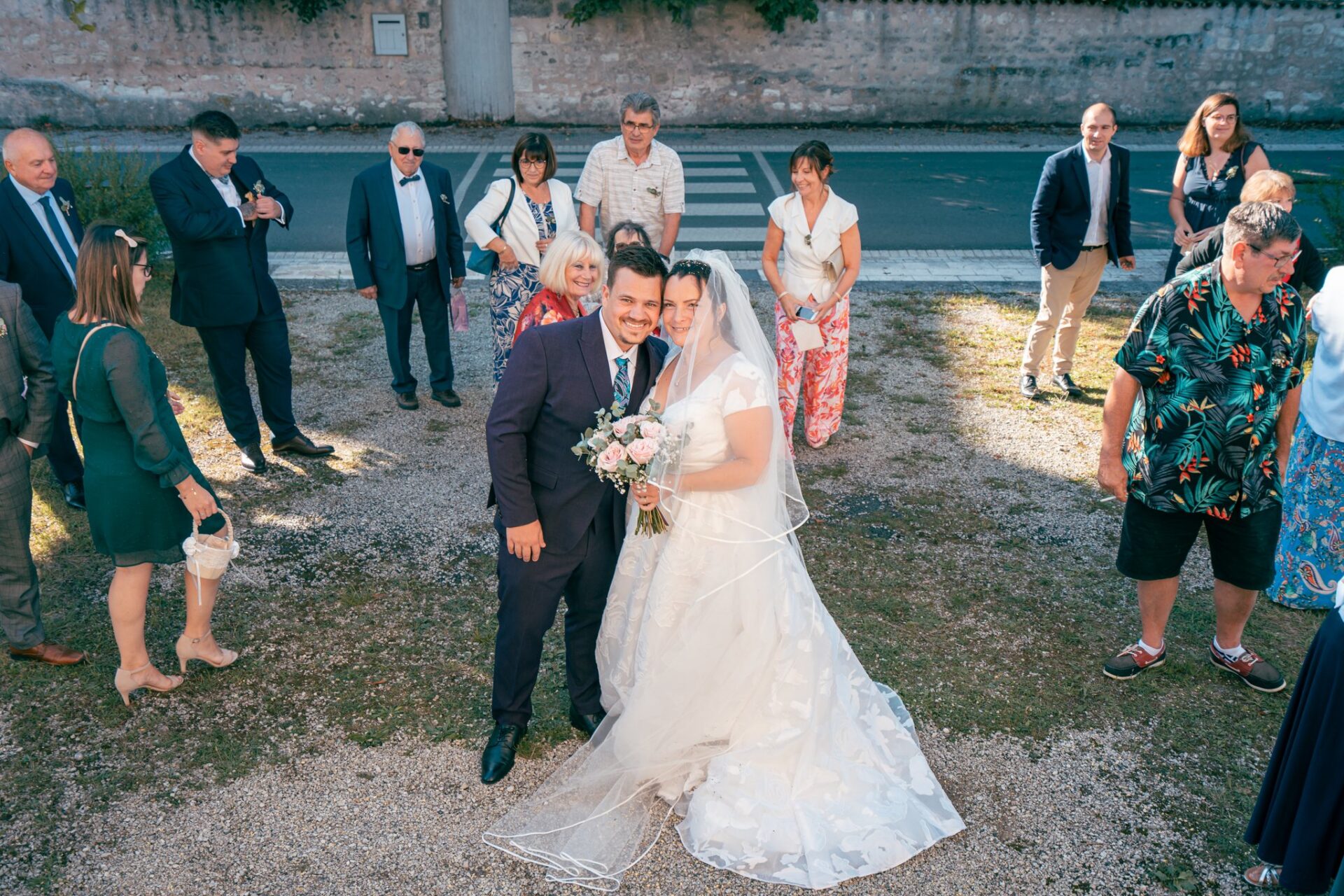 Le couple pose en souriant sur le parvis, entouré d'invités.