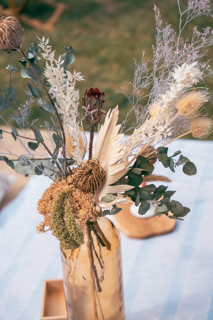 Un bouquet de fleurs séchées et de feuillages posé sur une table blanche.