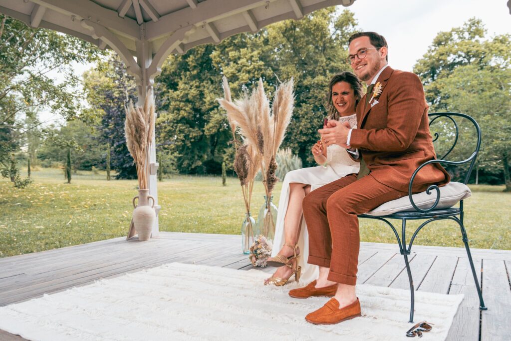 Le couple assis sous le kiosque rit, entouré de bouquets d'herbes de la pampa.