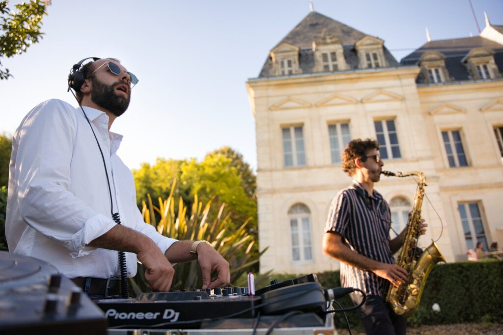 Un DJ et un saxophoniste jouent en plein air devant la façade du château, pendant le vin d'honneur.