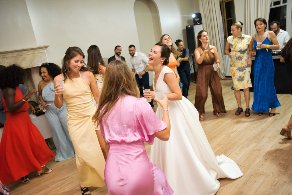La mariée danse avec des invités, sa robe tournant sur le parquet de la salle de bal.