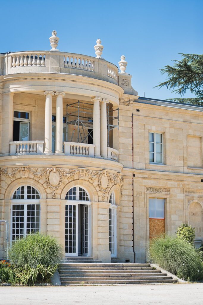 Façade en pierre de l'hôtel de ville de Talence, avec son balcon à balustres sous un ciel bleu.