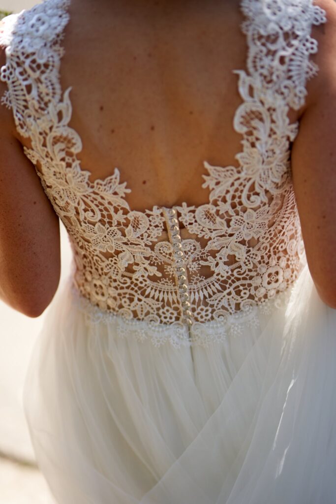 Dos d'une mariée en robe de dentelle ivoire à jupe de tulle.