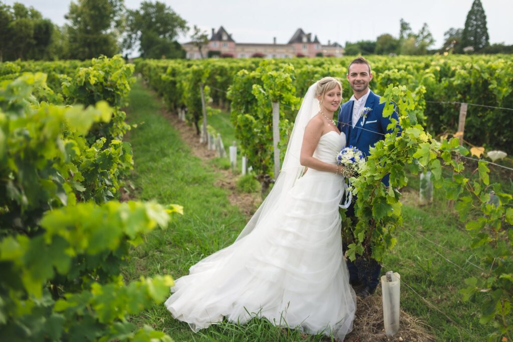 Couple de mariés dans un rang de vigne, le château visible au loin