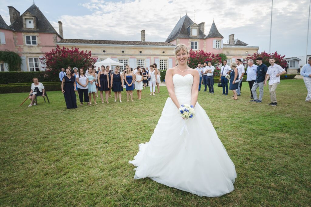 Mariée en robe blanche seule sur la pelouse, le château et ses haies taillées derrière