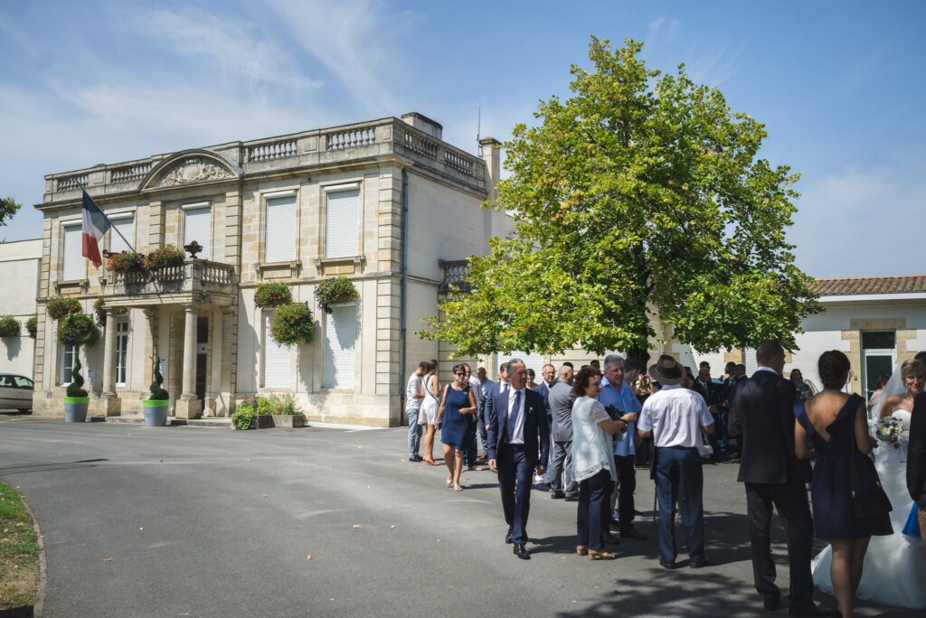 Façade de la mairie de Villenave-d'Ornon sous un ciel bleu, avec un groupe d'invités qui se rassemble devant.