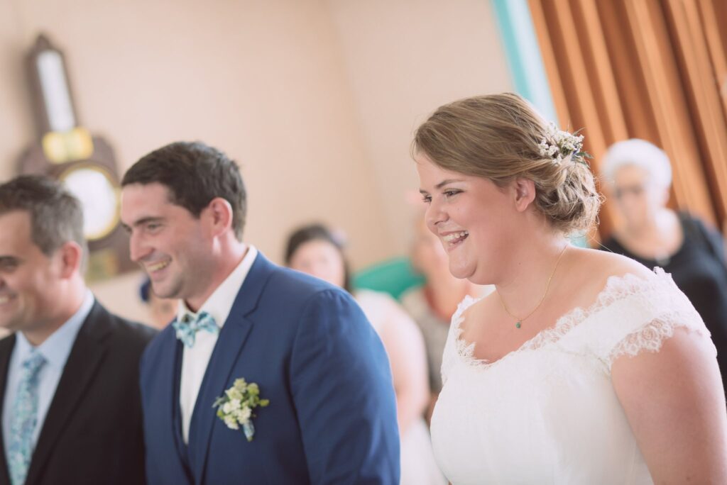 Le marié et la mariée côte à côte pendant la cérémonie civile, elle souriante.