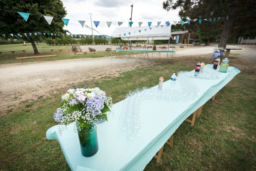 Une longue table turquoise dressée pour le vin d'honneur avec un bouquet, sous des fanions.
