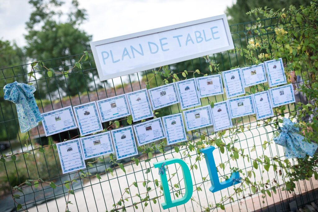 Un panneau de plan de table accroché à une grille, avec les lettres D et L en turquoise.