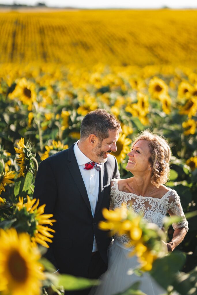Les mariés se regardent en souriant au milieu des tournesols.