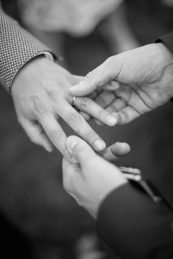 En noir et blanc, gros plan sur des mains et une alliance.