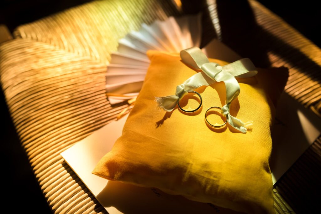 Deux alliances posées sur un coussin jaune orné d'un ruban.