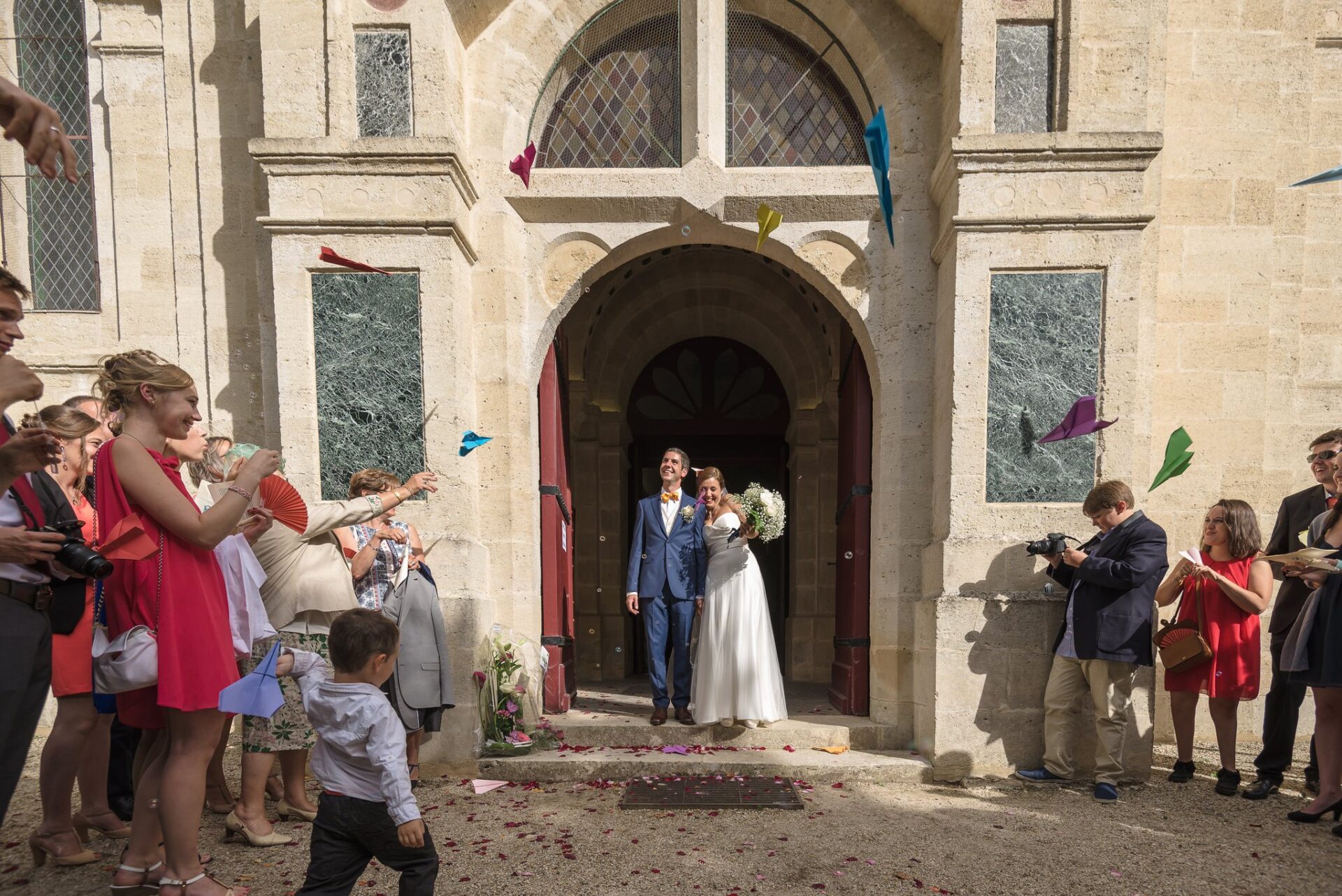 Les mariés sortent de l'église sous des confettis lancés par les invités.