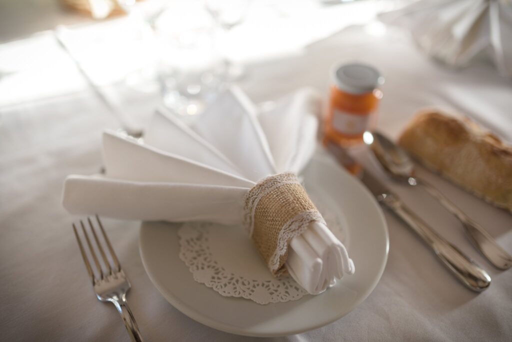 Une assiette dressée avec une serviette nouée d'un ruban de lin et du pain.