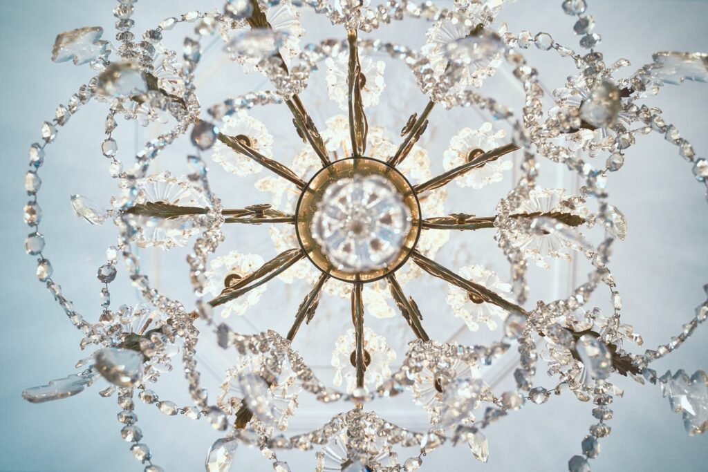 Vue du dessous d'un lustre ornemental à cristaux et éléments métalliques, devant un plafond blanc.
