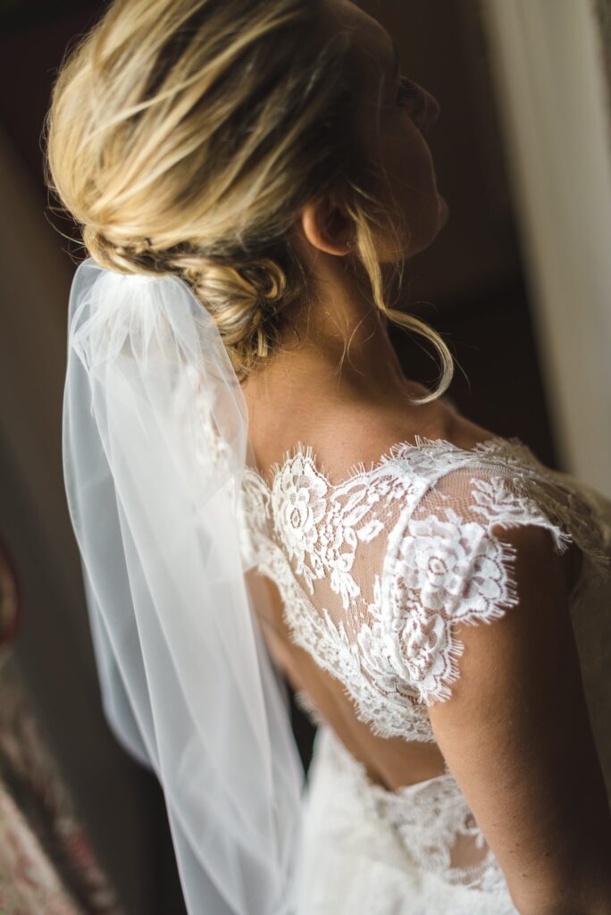 Le dos d'une mariée en robe de dentelle, coiffée d'un chignon et d'un voile.