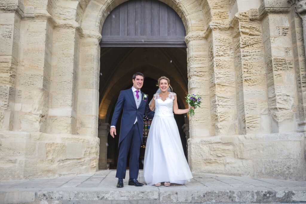 Les mariés posent à l'entrée d'un portail roman aux arcs sculptés.