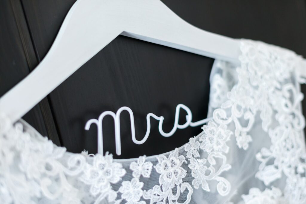 Une robe de mariée en dentelle sur un cintre blanc portant l'inscription « Mrs ».